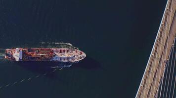 A top down aerial view of the tanker passing under a bridge video