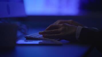 A person is quietly typing on a keyboard inside a dark, modern workspace environment video