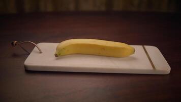 A vibrant yellow banana placed on a cutting board, situated in a cozy and inviting setting video