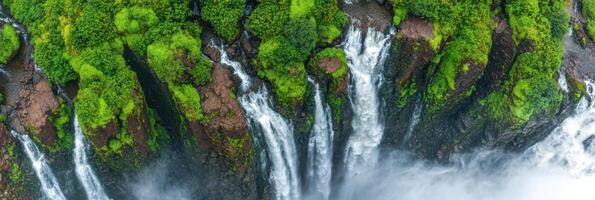 Majestic aerial view of waterfalls cascading through lush greenery and rocky cliffs photo