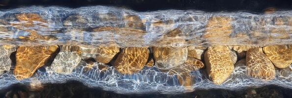 Tranquil stream with flowing water over colorful stones captured from above photo