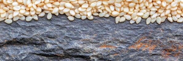 Close-up of sesame seeds arranged on rustic gray stone surface photo