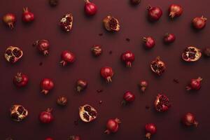 Pattern of whole and cut pomegranates on dark red background photo
