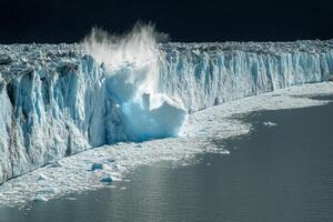 Glacier calving with splashing ice and melting snow into arctic ocean waters photo