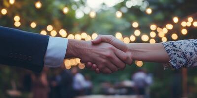 Business handshake between two people under twinkling string lights outdoors photo
