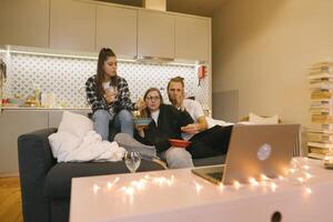 A Group of Friends Enjoying a Cozy Evening Together with a Laptop and Delicious Snacks photo
