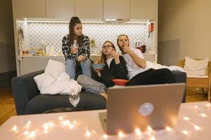A group of friends are happily enjoying a cozy movie night together on the comfortable couch photo