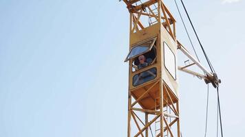 worker in the cockpit of a crane. building a house with a crane. video