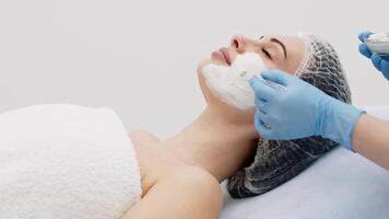 A cosmetologist applying anesthesia cream to a woman's face before a treatment. Concept of rejuvenation and anti-aging skin care. Perfect for content about cosmetic and anti-aging procedures video