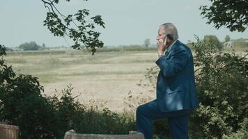 Man standing in garden with view on field calling with smartphone video