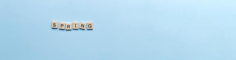 Banner The word spring laid out in wooden letters. Flat lay spring on blue background photo