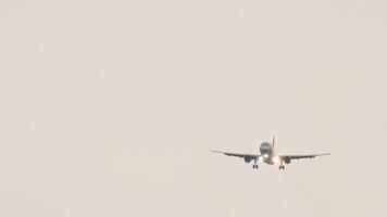 Unrecognizable jet plane with glowing lights approaching landing front view. Tourism and travel concept video