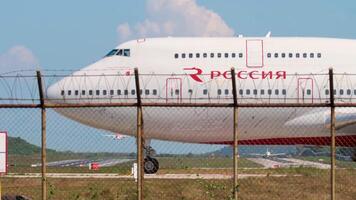 PHUKET, THAILAND DECEMBER 1, 2016 - Boeing 747 of Rossiya taxis at the start of the runway at Phuket International Airport HKT. Huge passenger airplane on the airfield, view through the airport fence video