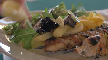 Close up view of meal on the plate, that woman waters lemon juice potatoes, salad and chicken barbecue video