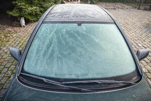 Nature drawings frost patterns on the windshield and on the roof of the car at below zero air temperature, abstract winter pattern, photo