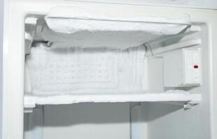 it's time to defrost the freezer compartment of the refrigerator, ice has formed on the walls and it is creeping out, icing of the cooling tubes, photo