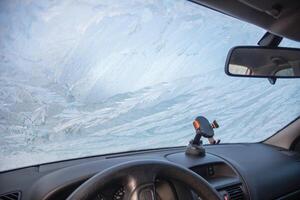 Frost patterns on the windshield of a car at subzero temperatures, view from the car interior of an abstract winter pattern and the steering wheel of a car, photo