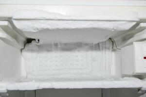 empty freezer compartment of the refrigerator, iced up on the walls with ice creeping out, defrosting required, photo