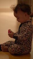 A curious and playful toddler is joyfully engaging with a colorful toy on the floor video