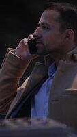 A professional man is on a phone call in an urban setting, showing confidence and style video