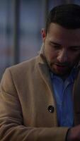 A thoughtful and contemplative man is in an urban setting, intently focused on his phone video