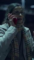 A woman is engaging in a phone conversation while in an urban setting during the night video