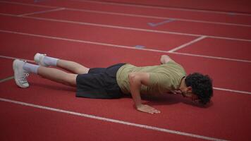 A man is doing pushups on a track, showing dedication to fitness and improving performance video