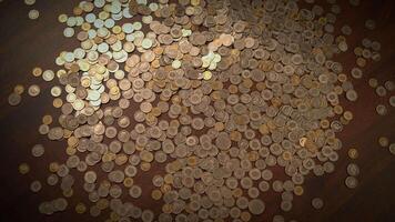 There are coins scattered across a wooden surface, waiting to be collected and counted video