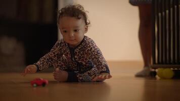 A curious baby is joyfully playing with a colorful toy car in a cozy and safe indoor setting video