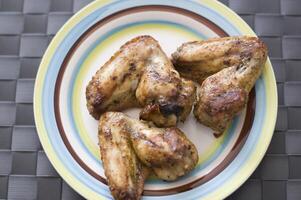 grilled chicken wings close up on the plate on the table, tasty unhealthy food concept photo