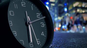 A closeup view of a clock with a vibrant city night background in the distance behind it video