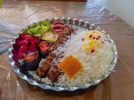 Savory Iranian kebab platter with fragrant rice and fresh veggies on a traditional plate photo