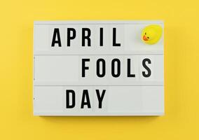 Lightbox Displaying April Fools Day With Green Leaves Against Bright Yellow Background, flat lay photo