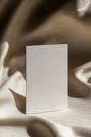 A vertical business card mockup standing upright on softly draped fabric with a subtle texture, illuminated by warm natural sunlight, creating a refined and minimalist aesthetic photo