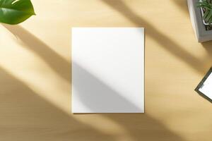 A minimalist A4 paper mockup placed on a wooden desk, surrounded by soft shadows, a green leaf, and a succulent plant, creating a clean and modern design with natural light photo