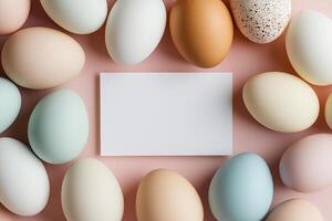 Colorful pastel easter eggs arranged around blank rectangular card on soft pink background photo