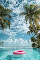 pink inflatable flamingo ring floats on blue water of pool with palm trees photo