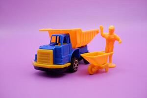 Toy Trucks and Mini Figures with Wheelbarrows on Purple Background photo