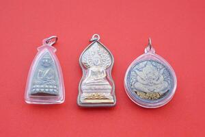 Buddha amulets on red background. Concept, faith and belief of Buddhist for holy to protect from danger, bring good luck, business prosperity and wealth. Collecting amulet as hobbies or exchange. photo