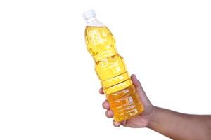 Hand holds bottle of cooking oil, isolated on white background. Extracted from seeds or from other parts of plants, such as sunflower seeds, soy beans, olive, palm fruits. photo