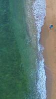 Aerial view of a man walking on the beach. Top view video