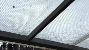 Heavy rain drumming on the transparent plexiglass roof. Beautiful rainy scene on summer day. Concept of tranquility nature scene. Close up Slow motion video