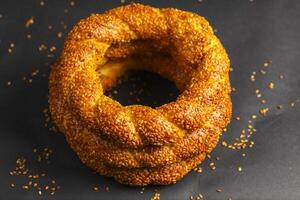 Freshly baked sesame-covered ring bread on dark background photo