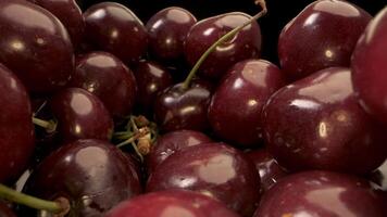 A close-up shot of a bowl filled with ripe, red cherries. The cherries are arranged tightly together, and their glossy surfaces reflect the light, creating a beautiful and inviting image. video