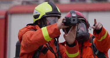 A group of specialized firefighters employs a thermal camera to locate and assess dangerous fire areas, demonstrating their advanced technology and expertise in effectively combating high-temperature video