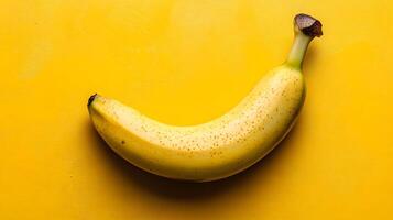 Single fresh banana positioned on yellow background creates vibrant monochromatic color scheme. Clean commercial food photography showcases minimalist composition in studio lighting. tropical photo