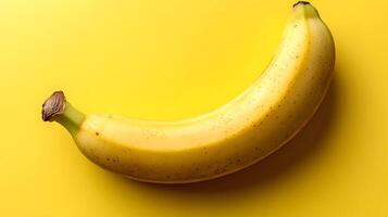 Single fresh banana positioned on yellow background creates vibrant monochromatic color scheme. Clean commercial food photography showcases minimalist composition in studio lighting. vibrant photo