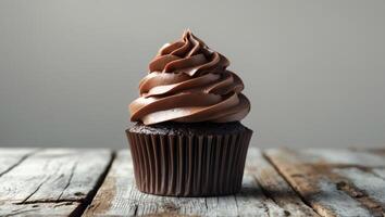 Delicious chocolate cupcake with creamy frosting and drizzled chocolate on a wooden table photo