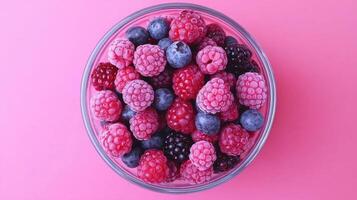 Frozen Mixed Berries in Glass Bowl Raspberries Blueberries Blackberries Pink Background photo