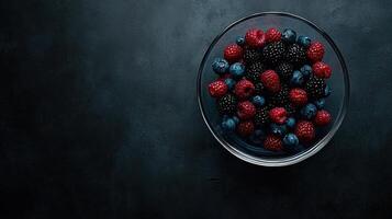 Fresh Raspberries Blackberries and Blueberries in Glass Bowl on Dark Background photo